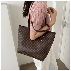 Detail of a large brown tote bag with geometric dot patterns and gold rivet straps