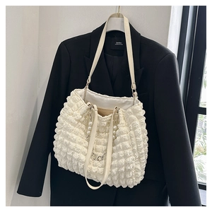 Detail of cream tote bag with bubble pleat texture, pearl charm and silver chain