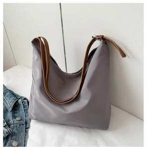 Detail of lavender nylon shoulder bag with brown leather strap and silver buckle hardware