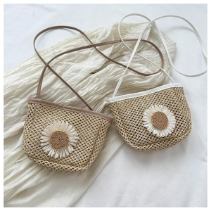 Detail of woven straw mini crossbody bags featuring large daisy accents and colorful leather trim