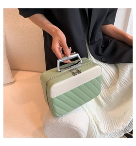 Close-up of quilted makeup bag with metal U-shaped handle and floral zipper pulls