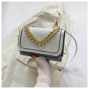 Close-up of color-block flap bag with woven texture, gold chain and purple body