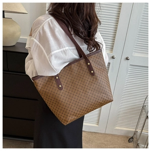 Brown geometric tote bag with leather handles shown over the shoulder in a modern room