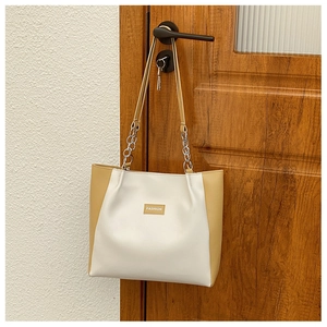 Détail du cabas bicolore avec étiquette FASHION et bandoulière en chaîne métal