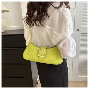 Sac baguette vert citron effet croco avec boucle dorée porté à l'épaule par le mannequin