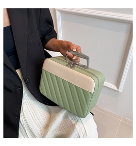 Detail of green quilted makeup bag with silver arch handle and floral zipper pull charm