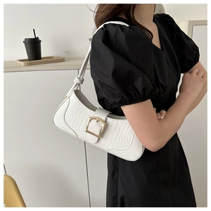 Gros plan d'un sac baguette blanc avec texture crocodile et boucle dorée chic