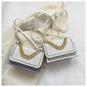 Detail of crossbody bag featuring woven texture and gold chain strap on soft fabric