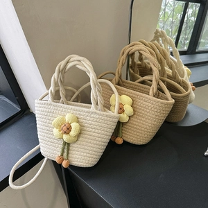 Fashionable woven straw bucket beach bags with decorative floral pendants for summer