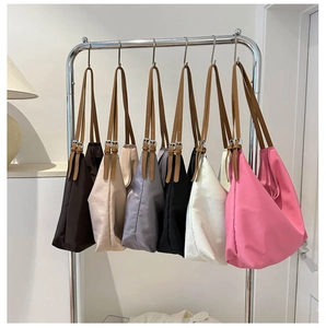 Row of colorful nylon tote bags hanging with adjustable leather straps in various colors