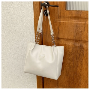 Gros plan d'un sac cabas blanc avec étiquette FASHION et chaîne en métal sur une porte