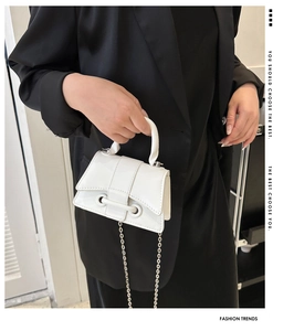 Detail of white patent leather handbag with silver chain strap and metal buckle