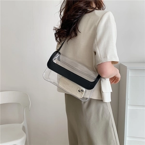 Sac à bandoulière chic en PVC transparent avec bordure noire porté par un modèle