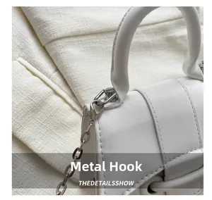 Macro detail of silver hardware hook and white stitching on a leather handbag