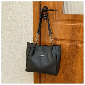 Détail du sac cabas en similicuir noir avec logo FASHION et bandoulière chaîne
