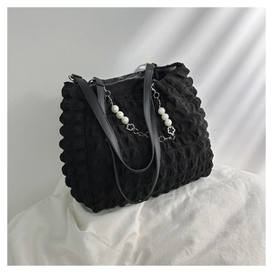 Detail of black tote bag with bubble texture fabric and decorative pearl metal chain