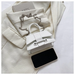 Mini white PU crossbody bag with silver chain strap shown next to phone for size reference