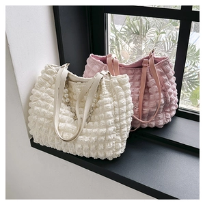 Detail of bubble pleated tote bag with pearl chain accessory and textured fabric