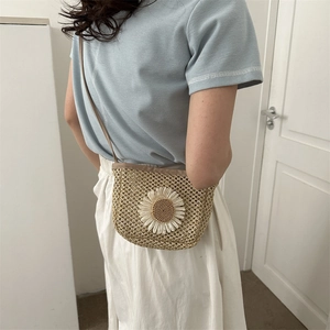 Minimalist beige woven straw crossbody bag featuring a white daisy flower decoration