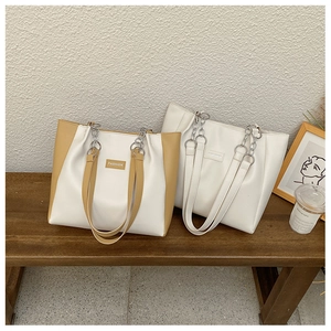 Détail de sacs fourre-tout color-block avec poignées en chaîne sur un banc