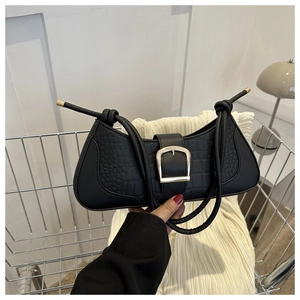 Détail d'un sac porté épaule noir effet crocodile avec une grande boucle en métal doré