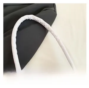 Detail of white quilted nylon bag featuring a thick padded handle and golden metal zipper