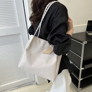 Chic beige houndstooth tote bag with braided straps shown in an indoor setting