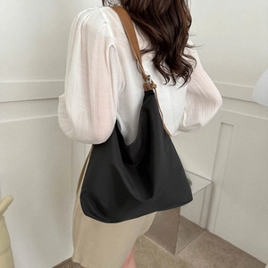 Large black Oxford fabric tote bag with brown shoulder strap shown on a model