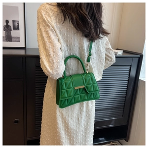 Dettaglio della borsa in pelle trapuntata verde brillante con fibbia dorata su un vestito