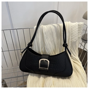 Détail du sac sous le bras noir à texture crocodile avec boucle argentée et bandoulière à nœud