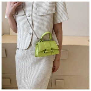 Detail of neon green micro handbag featuring silver chain strap and modern buckle design