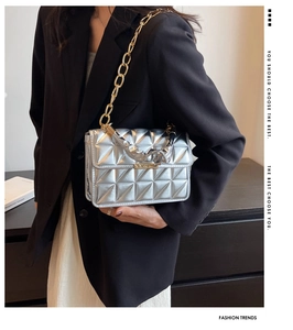 Close-up of silver quilted crossbody bag with gold chain strap and metallic finish