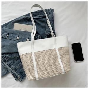 Top-down view of a minimalist woven tote bag with white leather trim on a stylish background