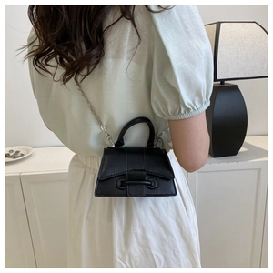 Detailed view of black PU leather handbag with perforated strap and silver chain strap