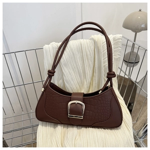 Détail du cuir gaufré crocodile marron foncé et boucle argentée du sac à bandoulière