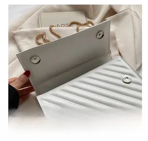 Dettaglio delle doppie chiusure magnetiche dorate su una borsa a tracolla trapuntata bianca