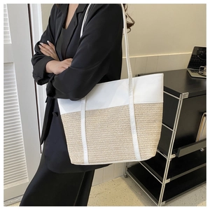 Chic woven tote bag in white leather and straw patchwork shown in a minimalist office setting