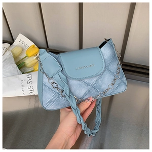 Detailed close-up of light blue denim texture and metal logo on this stylish shoulder bag
