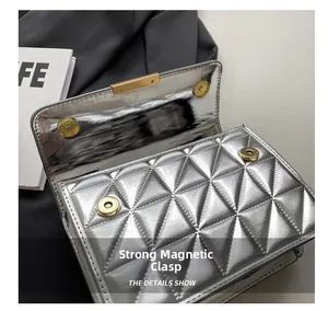 Detail view of strong magnetic gold buckles on a silver quilted leather flap bag