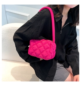 Hot pink quilted nylon shoulder bag shown with minimalist outfit on a sofa