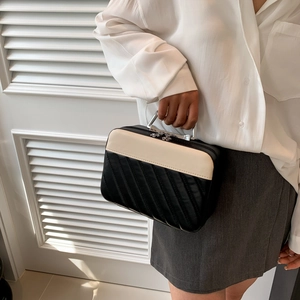Minimalist black and white quilted vanity case with silver metal handles in lifestyle setting