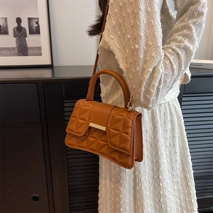 Elegante borsa a tracolla trapuntata color caramello con fibbia dorata su un modello