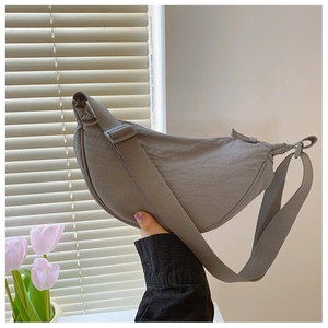 Macro detail of grey nylon dumpling bag texture with wide adjustable shoulder strap