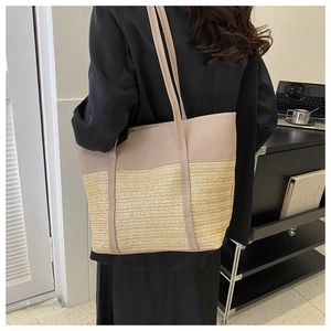 Detail of large woven tote bag in beige PU and straw texture worn by a model