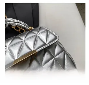 Macro view of silver quilted leather handbag with gold clasp and silk-wrapped handle detail