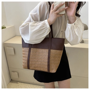 Detail of the two-tone tote bag featuring brown leather top and woven straw texture base
