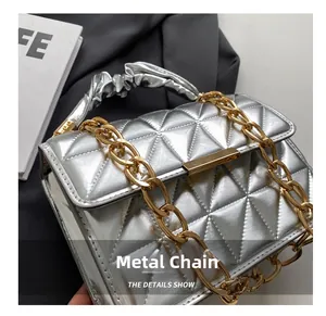 Detail of silver quilted handbag with chunky gold chain and ruffled handle design