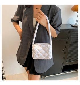 Detail of white quilted nylon shoulder bag with zipper closure and padded handle
