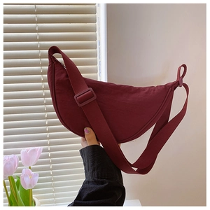 Detail of burgundy nylon crescent bag showing smooth fabric texture and wide strap