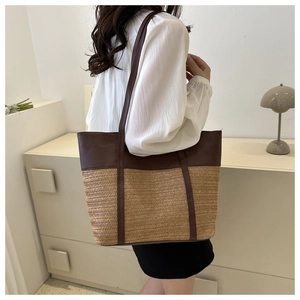 Detail of large tote bag showing textured straw weave and premium leather shoulder strap